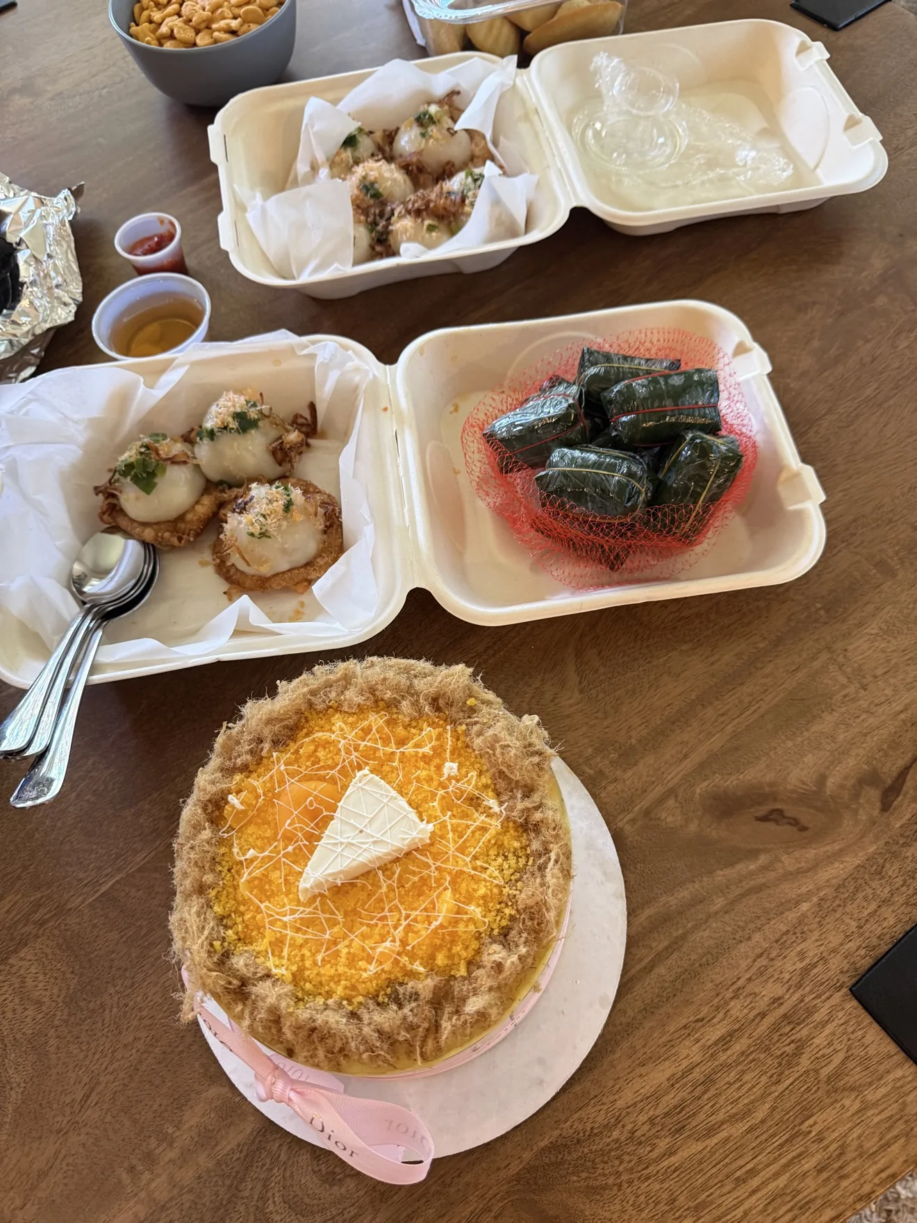 Homemade dumplings, leaf-wrapped dishes, and a cake arranged on a table