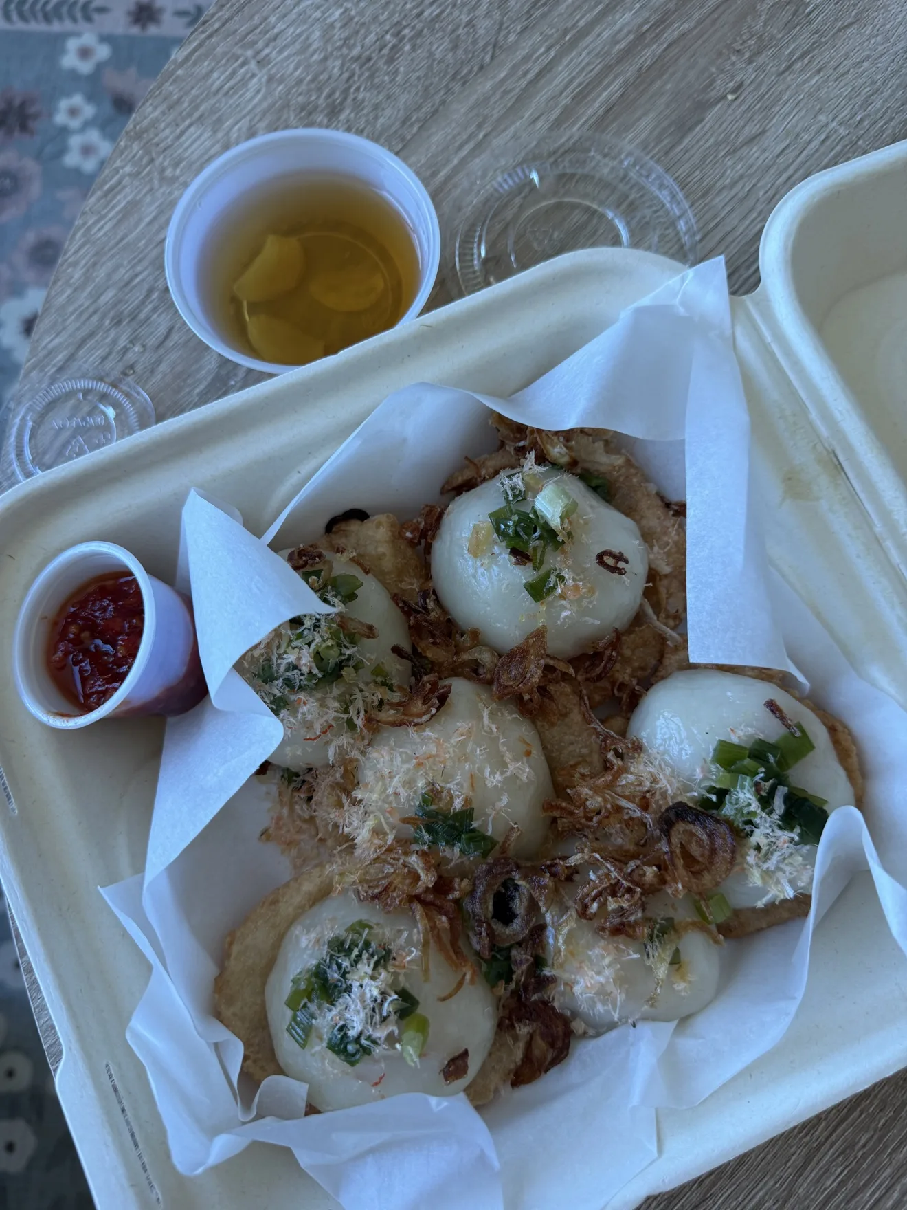 Savory cakes topped with scallions and fried shallots in a takeaway box