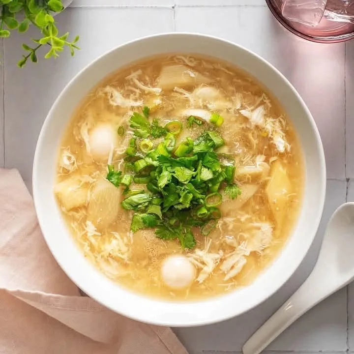 A bowl of golden soup topped with cilantro and black pepper